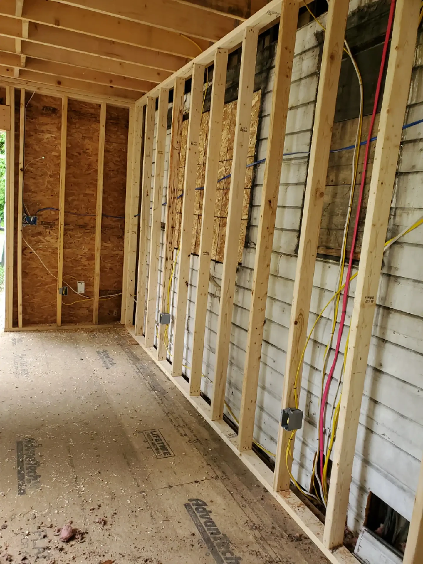 Cable runs and boxes on new studs against old siding in a home addition