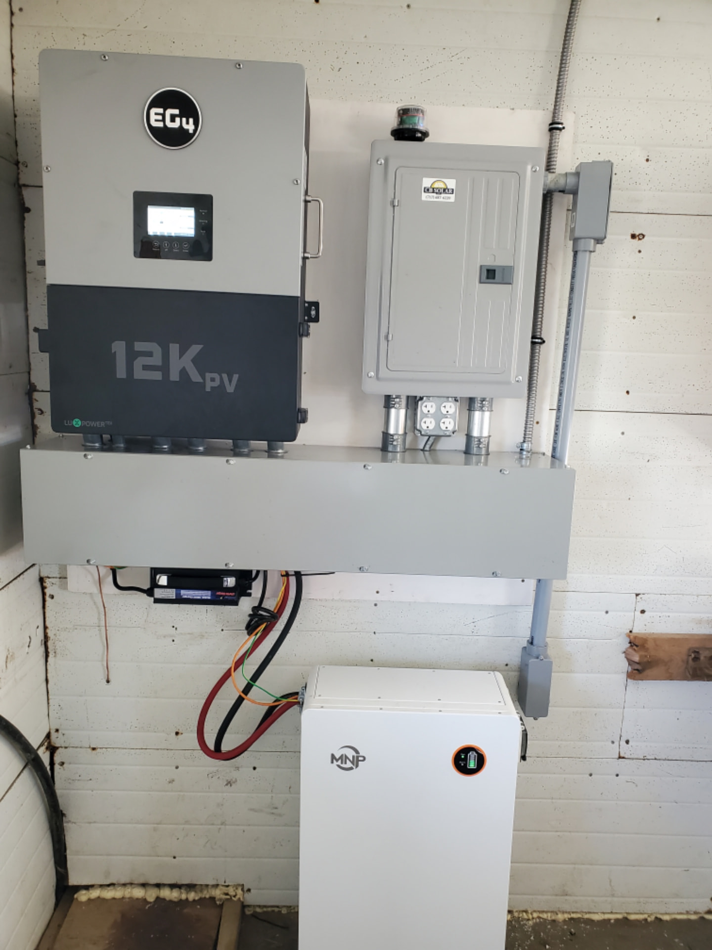 EG4 12K PV hybrid inverter and battery storage cabinet installed on an interior wall with conduit and a wiring trough
