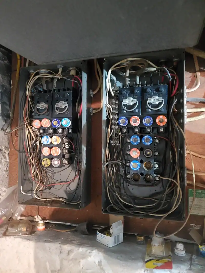 Two old fuse boxes with tangled cloth wiring before replacement